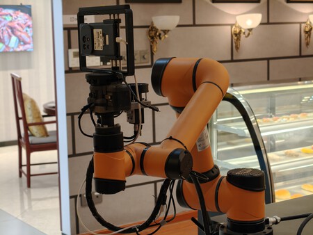 Detalle del brazo del robot donde puede verse un móvil en fase de pruebas | Imagen: Xataka